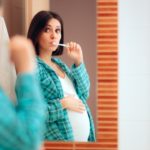 pregnant woman brushes her teeth