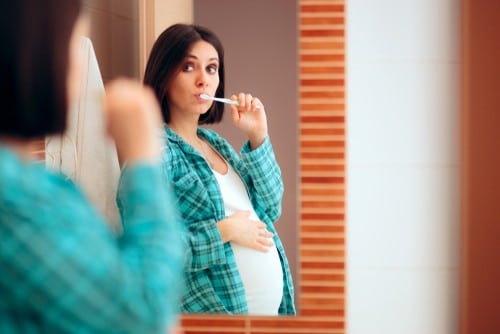 pregnant woman brushes her teeth