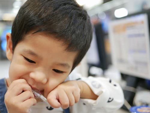 child opening bag with teeth