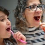 child and mom brushing teeth