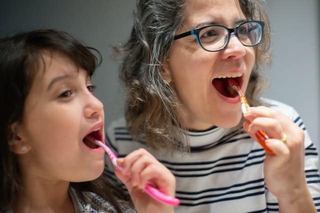 child and mom brushing teeth