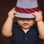 toddler hiding under hat