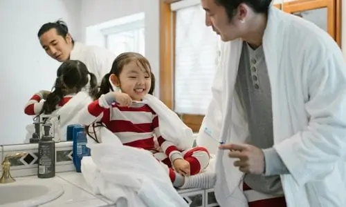 father brushes teeth with daughter